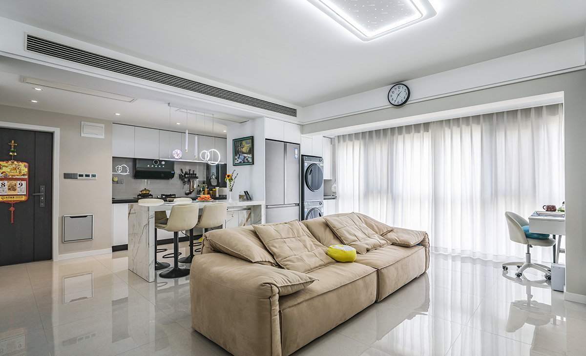 客廳面積不大，但經過設計師的手筆，采用了開放式廚房和客廳陽臺無縫銜接的設計，最大程度增加了房子的空間感。吊頂造型上采用時尚簡約的平頂雙眼皮吊頂設計，結合中央空調，讓造型更顯清爽，地面采用淺灰色地磚。造型和色調上無不給人以簡潔、大氣、時尚的感覺。