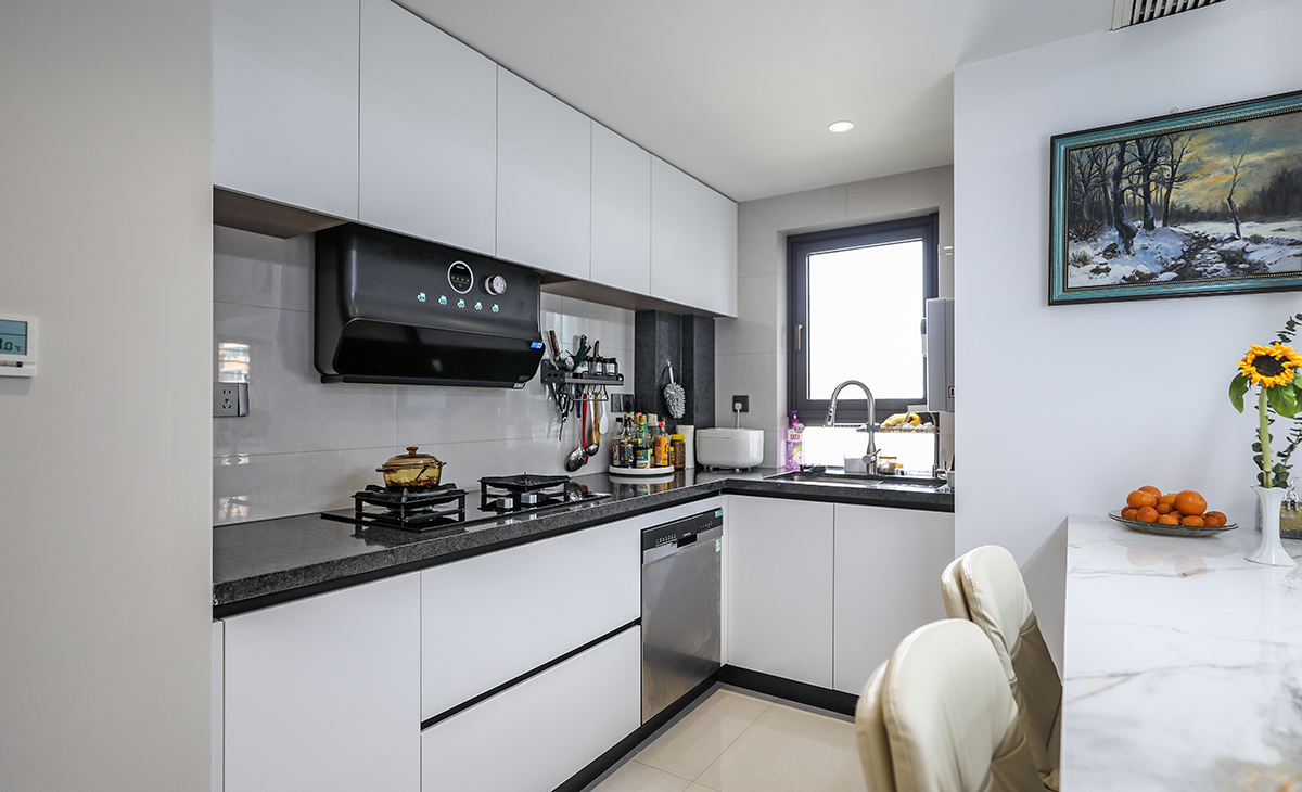敞開式廚房，L型櫥柜，洗、切、炒動線合理，白色的柜體、深灰的臺面和黑色的五金，顏色簡潔明快，材質干凈好打理。還安排了一個洗碗機解決了家里主人誰洗碗的煩惱。
