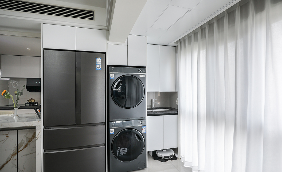 陽臺雖然和客廳融為一體，但它也有效的發揮了它改有的功能，洗衣機、烘干機、洗衣池、掃地機器人包括收納柜都給安排的妥妥的。