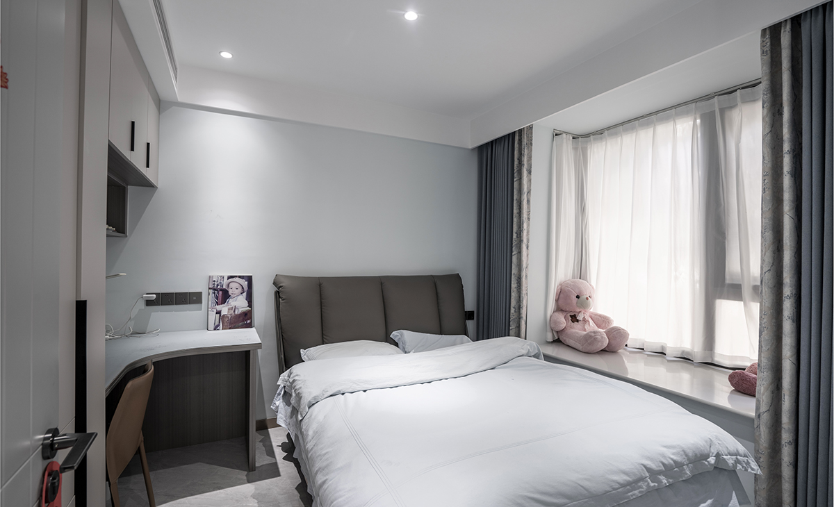 兒子房間有一個大飄窗，讓空間有延伸感，衣柜和書桌連成一體，既能掛衣服又能放學習用品，頂面采用無主燈設計，空間敞亮不壓抑。
