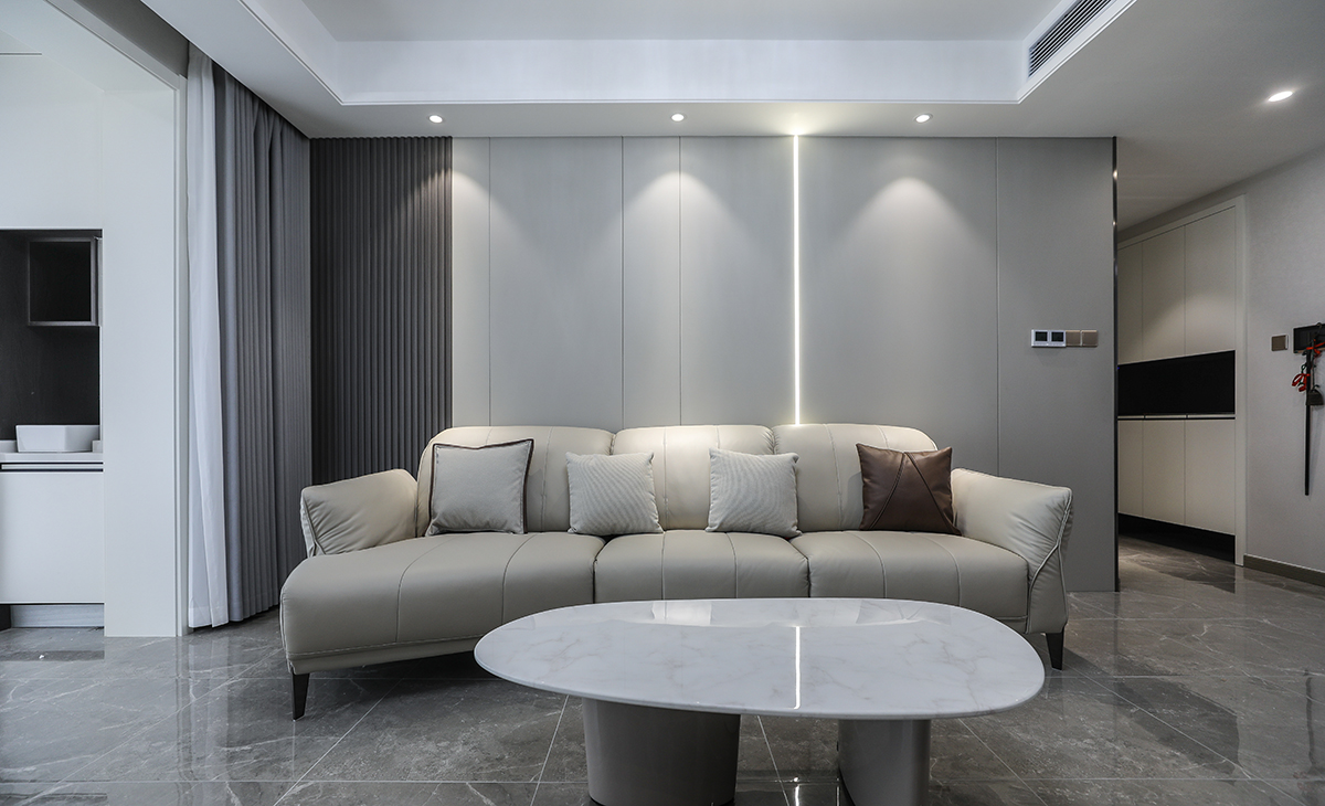 沙發背景刷米灰色涂料，白色的沙簾，沙發背景留白設計，色調上墻面涂料和窗簾用淺色，沙發用深色，深淺搭配的錯落有致，既溫馨又簡潔。