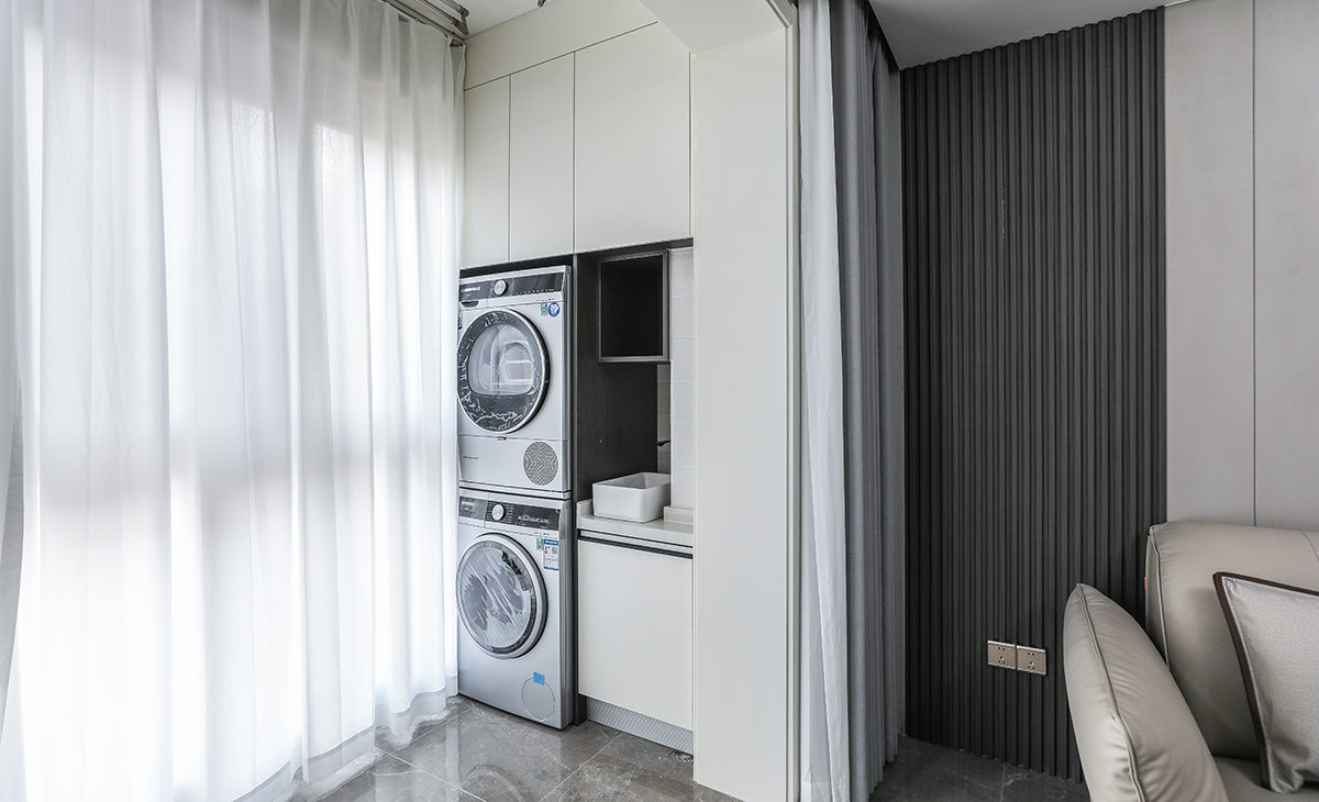 陽臺是晾曬衣物的場所，一側洗衣機和水池，一側為儲物柜，顏色以白色為主，儲物柜白色門板和門套相搭配，超大玻璃窗讓陽光柔和的照進來，很舒適、很愜意。