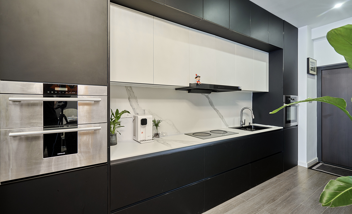 該套房子廚房空間很大，做成一字型櫥柜，蒸烤一體機(jī)，上柜下柜都是深灰色，白色的吊柜和巖板臺(tái)面，搭配的很大氣，客戶不斷地夸贊設(shè)計(jì)師對(duì)色彩的精準(zhǔn)把握。