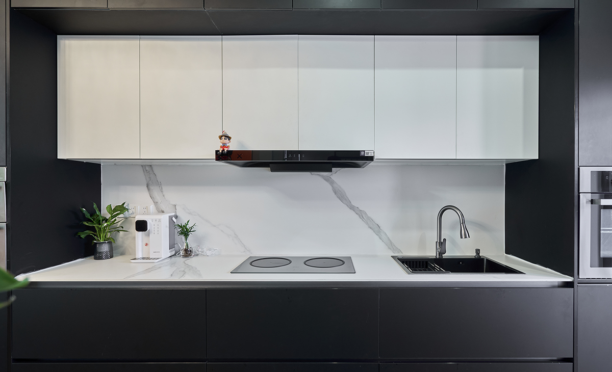 該套房子廚房空間很大，做成一字型櫥柜，蒸烤一體機(jī)，上柜下柜都是深灰色，白色的吊柜和巖板臺(tái)面，搭配的很大氣，客戶不斷地夸贊設(shè)計(jì)師對(duì)色彩的精準(zhǔn)把握。