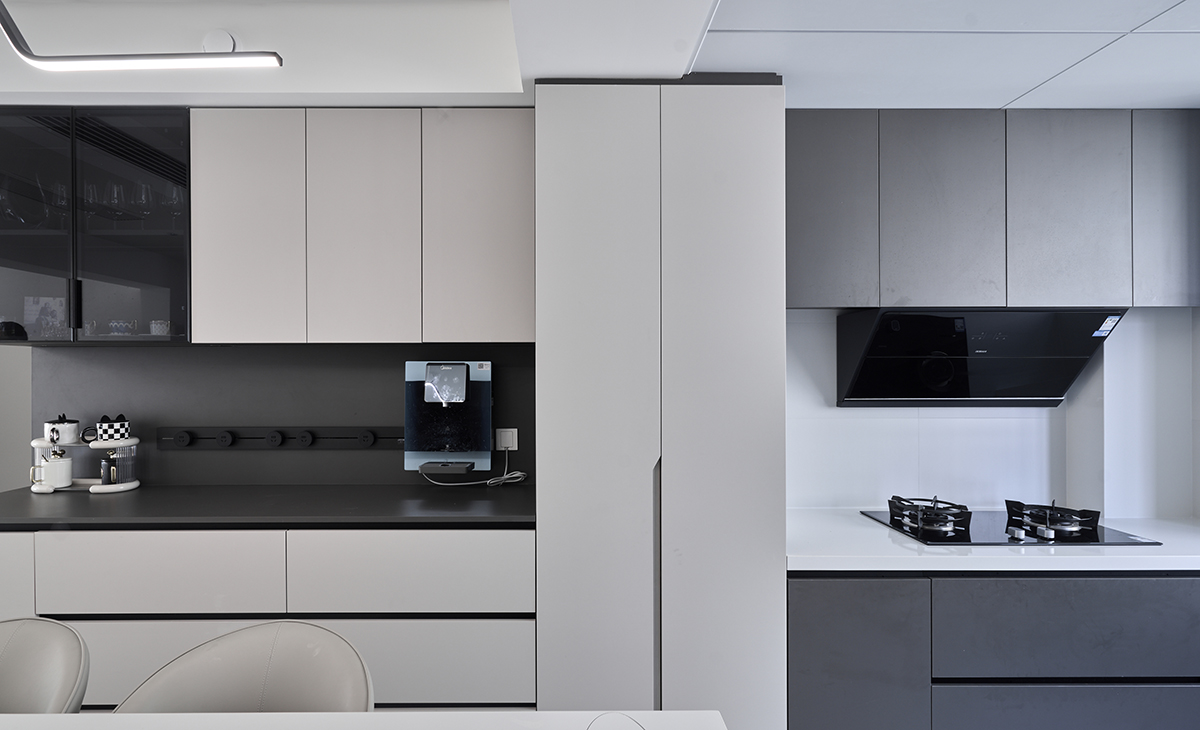 該套房子廚房空間很大，做成U字型櫥柜，蒸烤一體機放立柜中，煤氣灶下方配雙層碗籃、調味籃，上柜下柜是深灰色，臺面白色，方便打理，墻地磚的顏色和櫥柜顏色搭配地很自然，客戶不斷地夸贊設計師對色彩的精準把握。