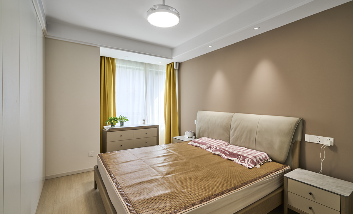 主臥鋪的暖灰色地板，背景墻咖色，這樣和地板進行搭配，就不會那么突兀，吊頂做雙眼皮，配合上背景墻燈，整體造型以簡潔平板為主，方便打理，體現了簡約風格的簡潔、隨意，不拘一格。