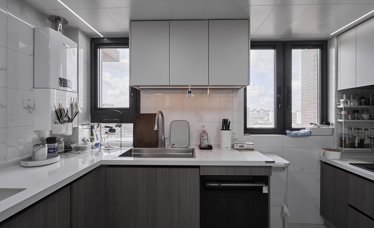 廚房空間很大，U型兩面櫥柜，顏色簡潔明快，材質要干凈和好打理，白色的吊頂和高光的的灰色櫥柜相呼應，石英石臺面干凈清爽，各種廚房電器全部配齊，滿足主人制作各種美食的需求。