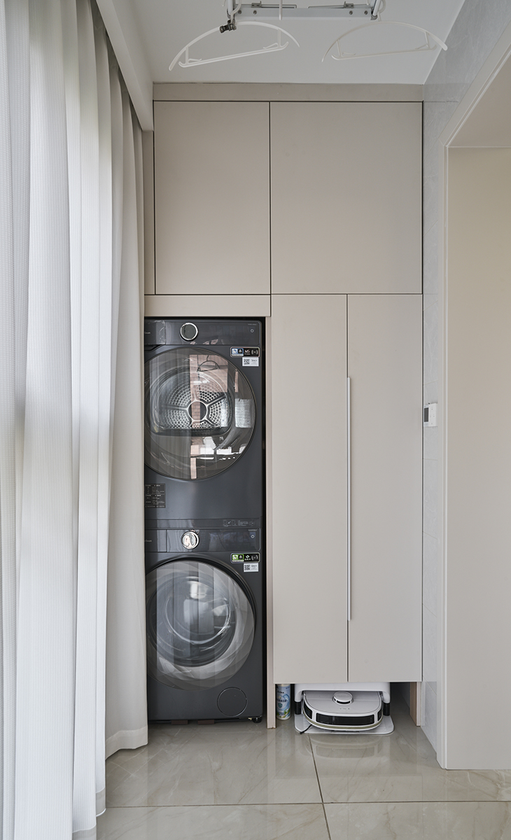 陽臺是晾曬衣物的場所，一側為儲物柜，洗衣機烘干機上下疊加，儲物柜顏色以淡色為主，超大玻璃窗讓陽光柔和的照進來，很舒適、很愜意。