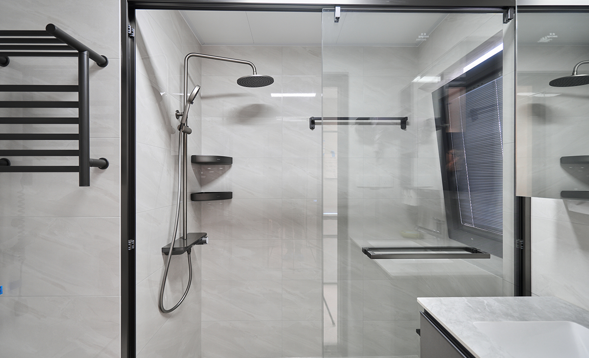 衛生間空間不大，采用槍灰色淋浴房邊框和槍灰色臺盆柜相呼應，淺灰色地磚，白色臺面，讓衛生間空間顏色明暗有序，從深到淺，色調很豐富。

