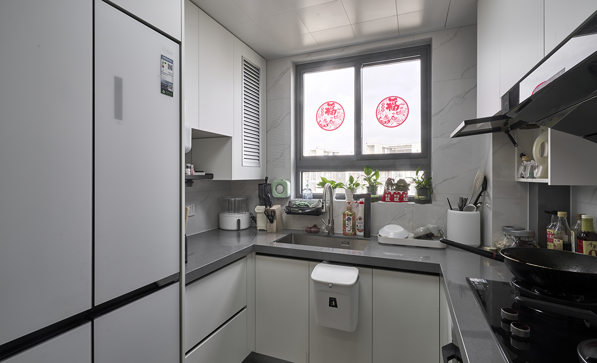  靠窗設(shè)計(jì)保證充足光亮；右邊黑色主打的廚房區(qū)域，櫥柜和油煙機(jī)選用深沉黑色。