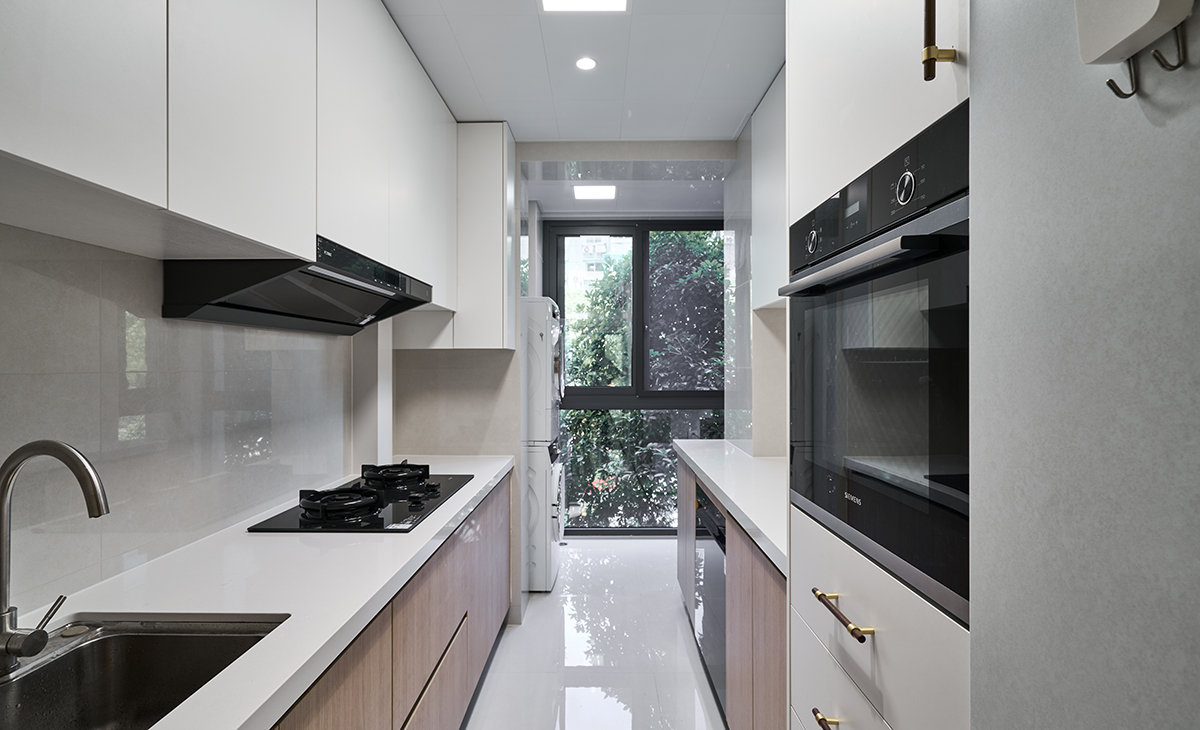 該套房子廚房空間很大，兩排操作臺面，電器立柜很方便、很實用，上柜是白色，下柜是原木色，臺面白色，方便打理，墻地磚的顏色和櫥柜顏色搭配地很自然，客戶不斷地夸贊設計師對色彩的精準把握。