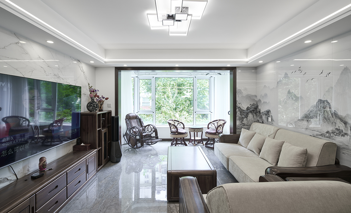 客廳是接待客人的空間、是家庭裝修的亮點所在、也是一家人活動頻率最高的區域，米色皮質沙發和白色山水畫巖板相呼應，體現高端華貴，吊頂造型上采用方形石膏板+雙眼出線型燈，實木電視柜和茶風、條幾上放一裝飾擺件。地面采用灰色玻化地磚。造型和色調上無不體現新中式風格的厚重和高貴。