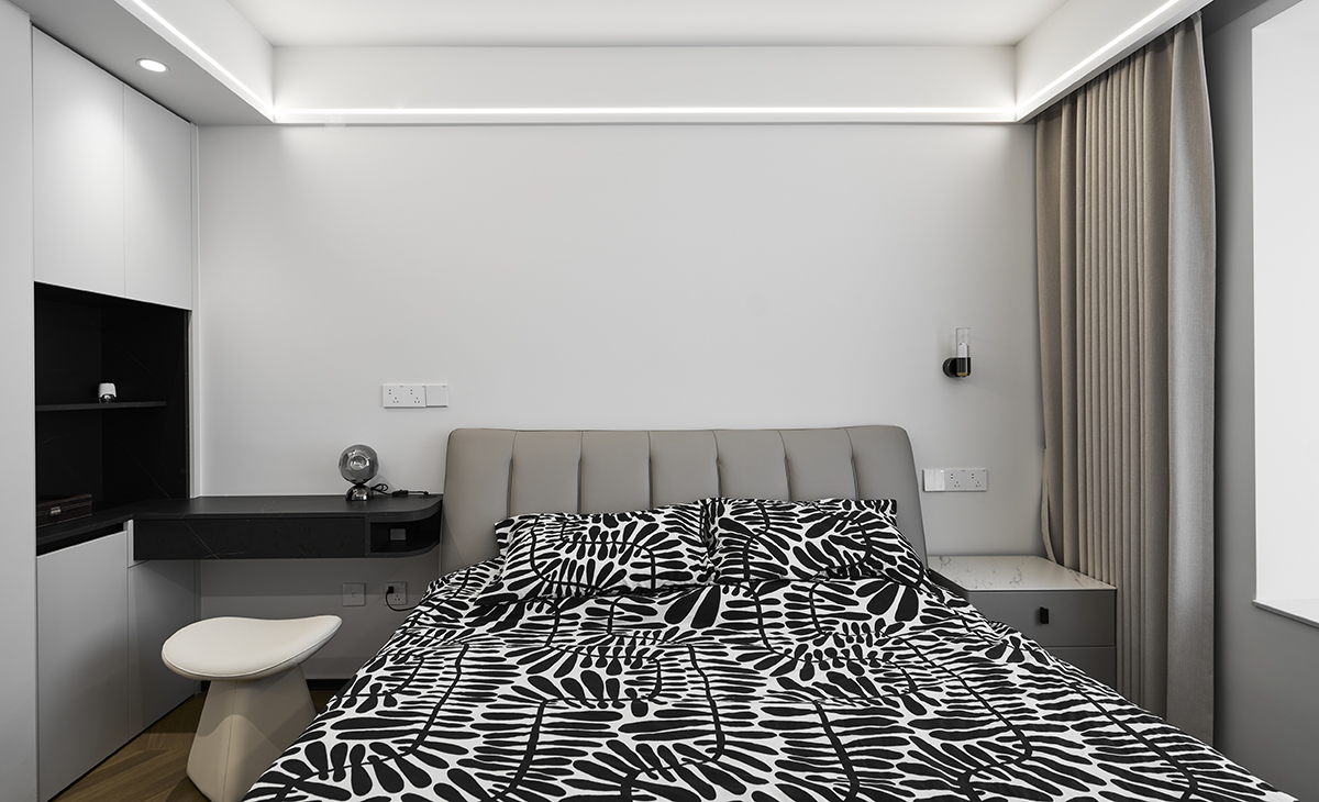 延續(xù)主臥的雅致格調(diào)，次臥以簡凈的線條與溫潤的木質(zhì)勾勒出同樣寧靜的休憩空間。床榻左側(cè)與前方，衣柜與儲(chǔ)物柜悄然延伸，既滿足收納之需，又以利落的體塊構(gòu)成視覺平衡。右前方，一方木質(zhì)書桌臨窗而立，在自然光線的輕撫下，成為閱讀或冥想的詩意角落。