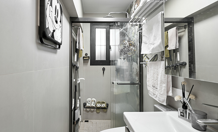 衛生間采用干濕分離的布置，淺灰色墻磚配白色浴室柜和黑色邊框長虹玻璃移門，顏色明暗有序，從深到淺，色調很豐富，掛墻臺盆柜，墻排水設計，下方又設計一個地漏，顏色協調統一，主人很滿意。  