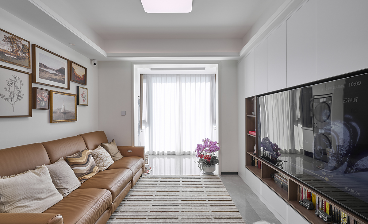 客廳是接待客人的空間、是家庭裝修的亮點所在、也是一家人活動頻率最高的區域，淺棕色皮質沙發和白色山水畫巖板相呼應，體現高端華貴，吊頂造型上采用方形石膏板+雙眼皮造型，對面一排電視組合柜，增加了收納功能。地面采用灰色玻化地磚。造型和色調上無不體現現代風格的厚重和高貴。