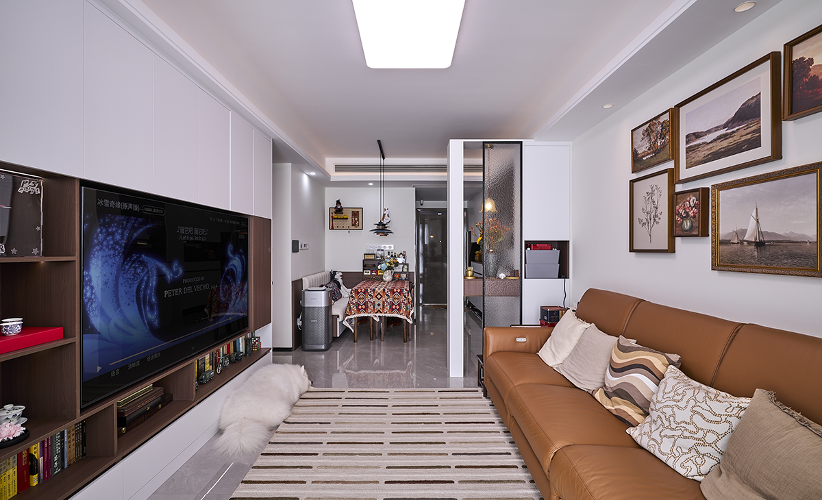 淺胡桃色和白色相搭配的電視組合柜，和頂面吊頂造型相呼應，沙發邊上小柜子可以收納小東西，頂上見光不見燈，沙發前面一塊大地毯，讓主人可以隨時練瑜伽，體現了客戶良好的生活方式。
