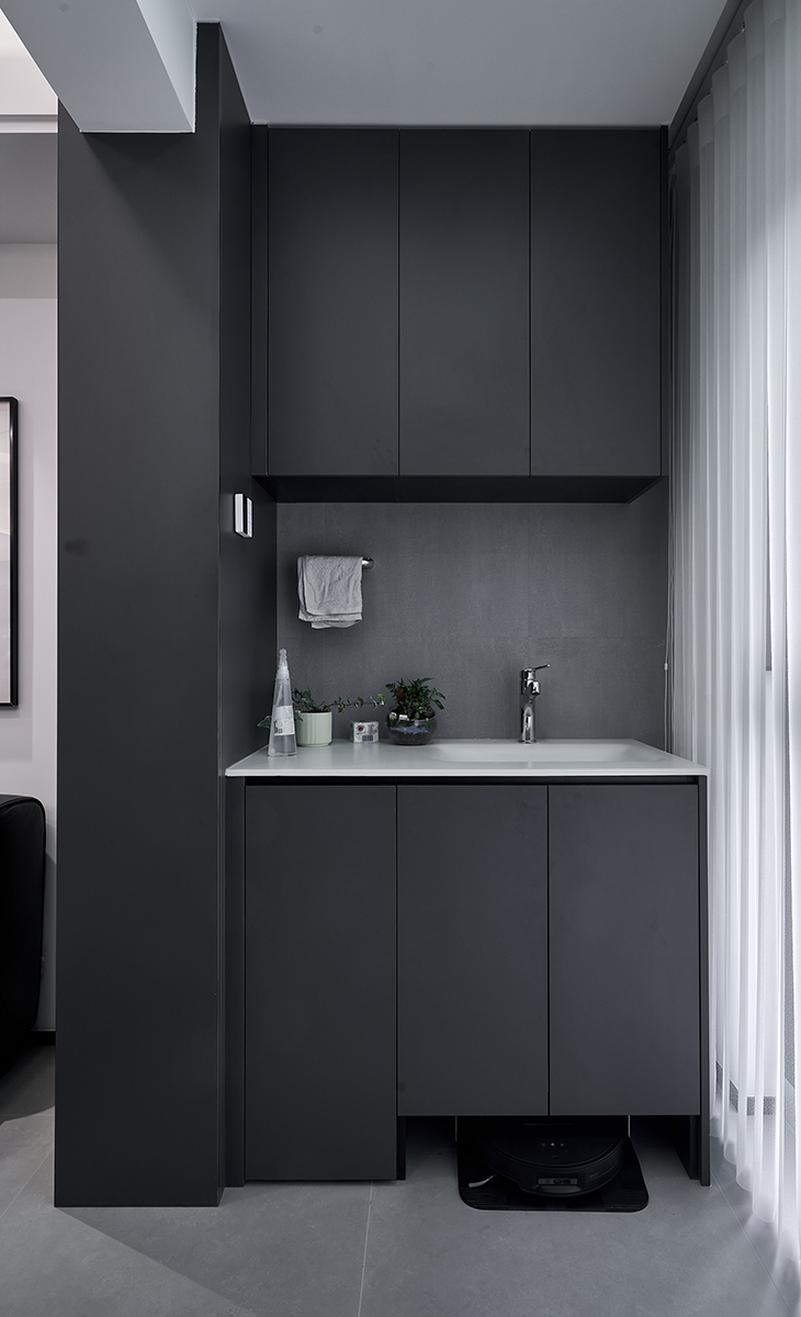 銜接整體空間的現(xiàn)代暗調(diào)風(fēng)格，以 “家政功能 + 輕休閑” 為核心，將陽(yáng)臺(tái)打造為 “隱形家政區(qū) + 小型放松角”，既滿足日常家務(wù)需求，又兼顧空間美學(xué)。