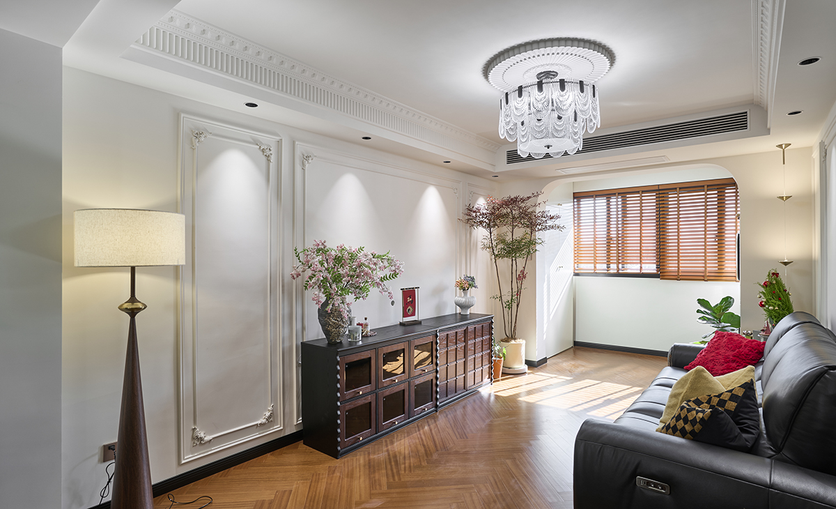 客廳是接待客人的空間、是家庭裝修的亮點所在、也是一家人活動頻率最高的區域，黑色皮質沙發，人字拼木紋復古地板，吊頂造型上采用回字頂+成品石膏虎頭線+鋼琴線，古木色的電視柜，陽臺拱形門洞。自然光透過落地窗灑落，與暖色燈光交織，營造溫馨社交氛圍