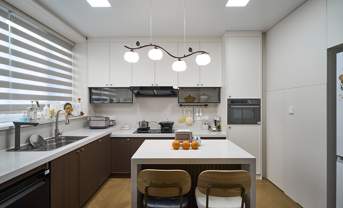 胡桃木裹著暖光，黃銅拉手碰著煙火廚房，是復(fù)古調(diào)里的人間煙火氣。
百葉窗篩碎的光，落在樹枝吊燈的奶白球上，連洗個(gè)碗都像在復(fù)古電影里。