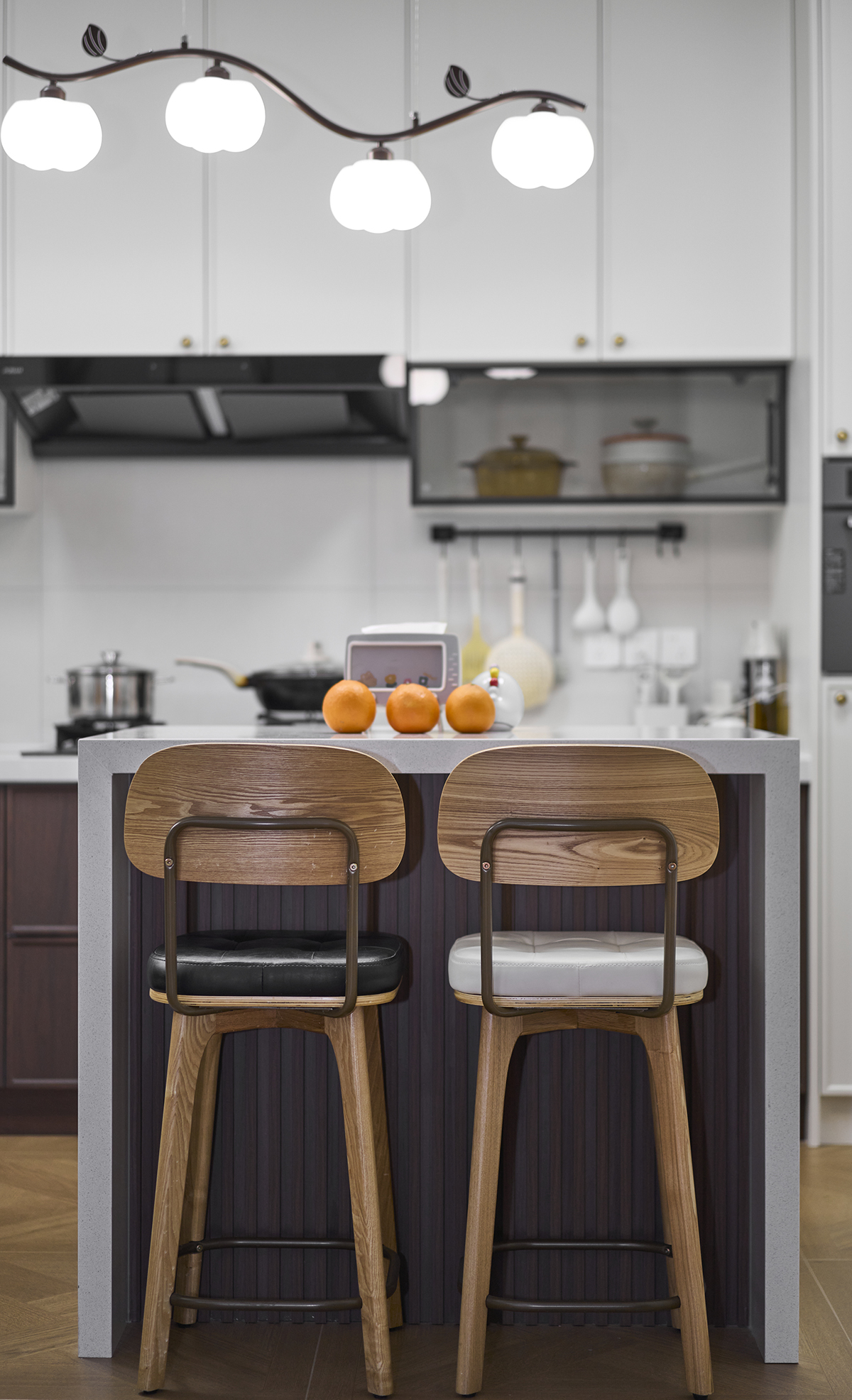 黑白椅挨著煙火氣  這方寸小臺(tái)，是中古調(diào)里的早餐與閑，吧臺(tái)沿的淺白，碰著木椅的暖棕；隨手放的橘子，是復(fù)古廚房最鮮活的小點(diǎn)綴