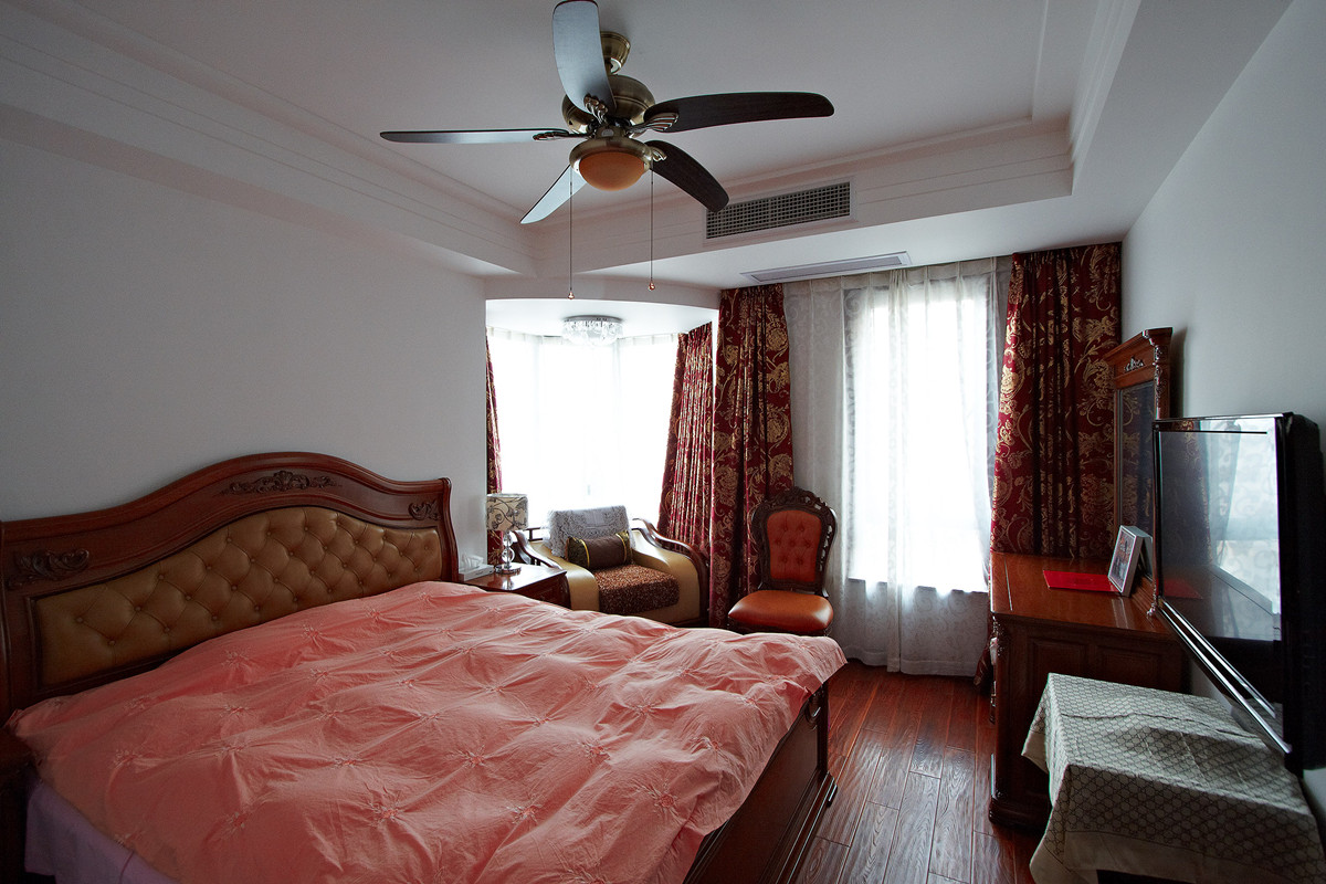 主臥奢華低調，現代韻味的吊扇，集休閑與休息與一體，紅色帶花的窗簾，配上紅木色的家具，使得中式的傳統文化表現的更加到位，簡單的紅木家具是主人的品味獨特體現。