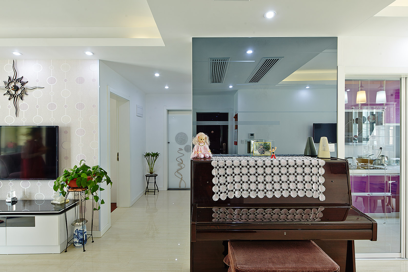 由于房型關系，進門右邊就是餐廳，設計師利用對面的灰鏡和鋼琴分割客餐廳的區分，為本來沒有辦法分割的區域巧妙的劃分了一下，完全不占用空間。更使空間寬敞而亮麗。