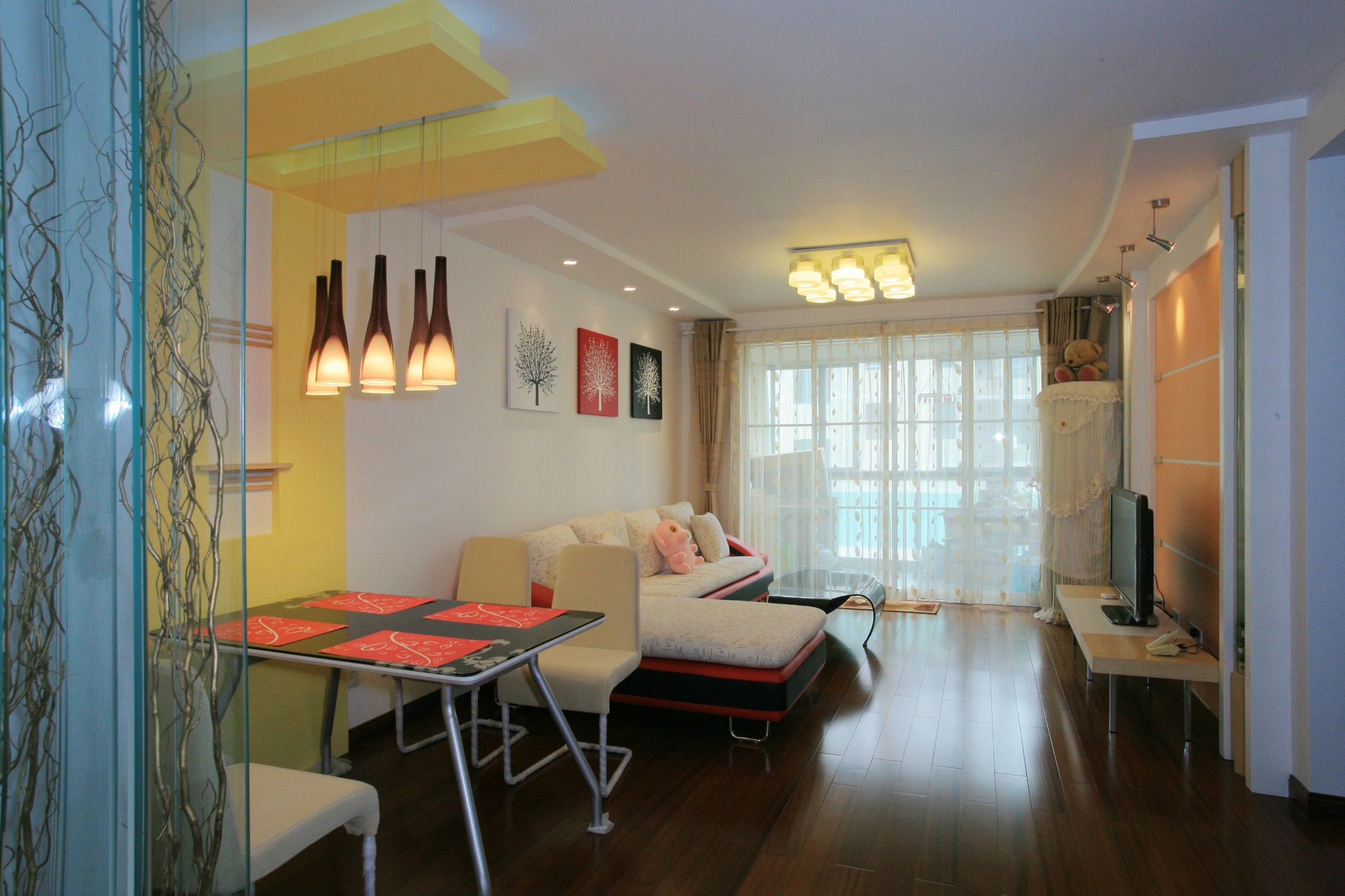 客廳的布局是整個居室中最出彩的地方，本案中無論是天花還是背景墻，都沒有作過多的裝飾，簡單明了的線條 ，使空間得到很好的延伸，鮮艷的色彩也為居室增添了一分活躍的氣氛。黃色的燈光中還有幾分靜謐與溫馨。
