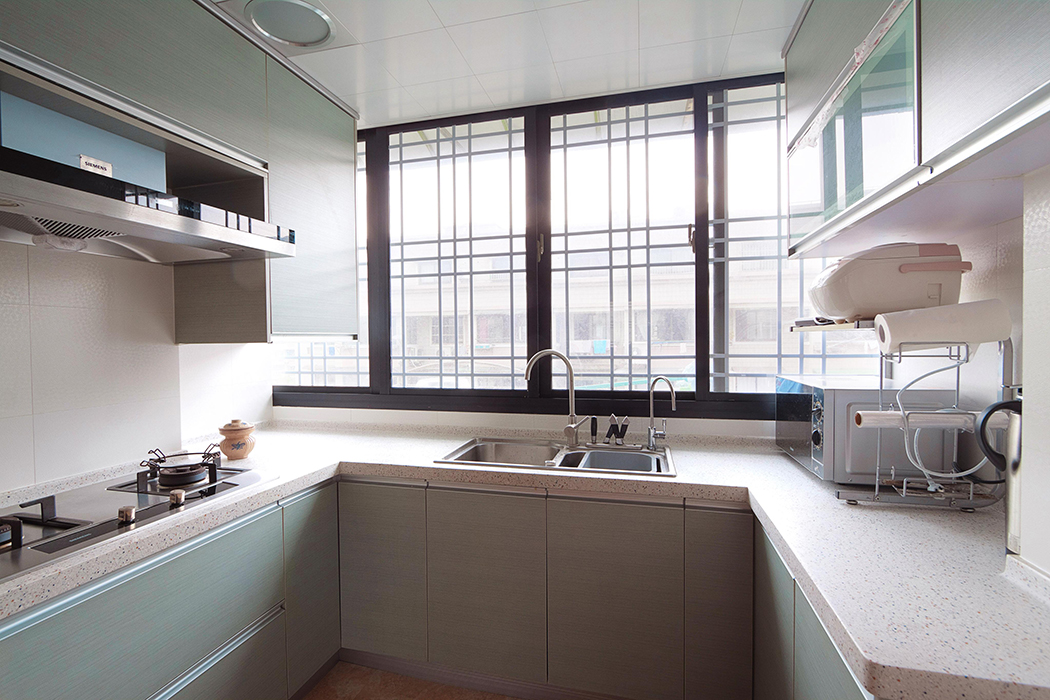 廚房間的搭配可算是別有用心，水槽處的柜面使用的是淺色的木色，呼應客廳處的木色，其余的柜體使用淺淺的綠色，使人心情愉快。
