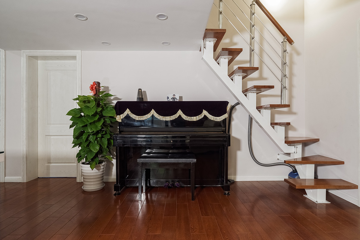 客廳為了配合業主家的米白色沙發，地面采用了環保的實木地板，家具采用黑白系列，簡單干凈。沒有過多的裝飾，頂面沒有做過多的修飾主要考慮到業主的房型是loft，需要搭建，吊頂的話會壓低層高也會使人不舒服所以頂面不做過多裝飾。電視背景墻采用灰色的地板上墻，給人以穩重的感覺，客廳樓梯采用的是經濟實用的鋼木樓梯，同時讓整個客廳顯得不那么單調。
