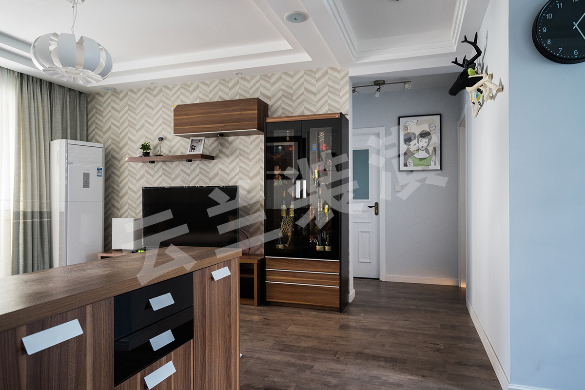  現(xiàn)代人們越來越喜歡簡單化的家具，它舒適更便于打掃，所以客廳的家具雖保持著美式的沉穩(wěn)顏色，但是沒有了繁瑣的花紋和配飾。那更多美式的元素就是藏在與吊頂和立面簡單的畫框線條。他的吊頂更多的是層層疊加，讓整個立面看上去更立體。再配上客戶花心思淘的配飾和掛畫，讓整個空間一下子生動了起來。客廳的整個立面設計都已經簡單化，已有了沙發(fā)背景的線條框，所以電視背景只采用了簡單的墻紙來修飾在配上組合柜來豐富整個格局。最后加上顏色亮麗的掛畫和抱枕讓整體空間都生機勃勃了起來。
