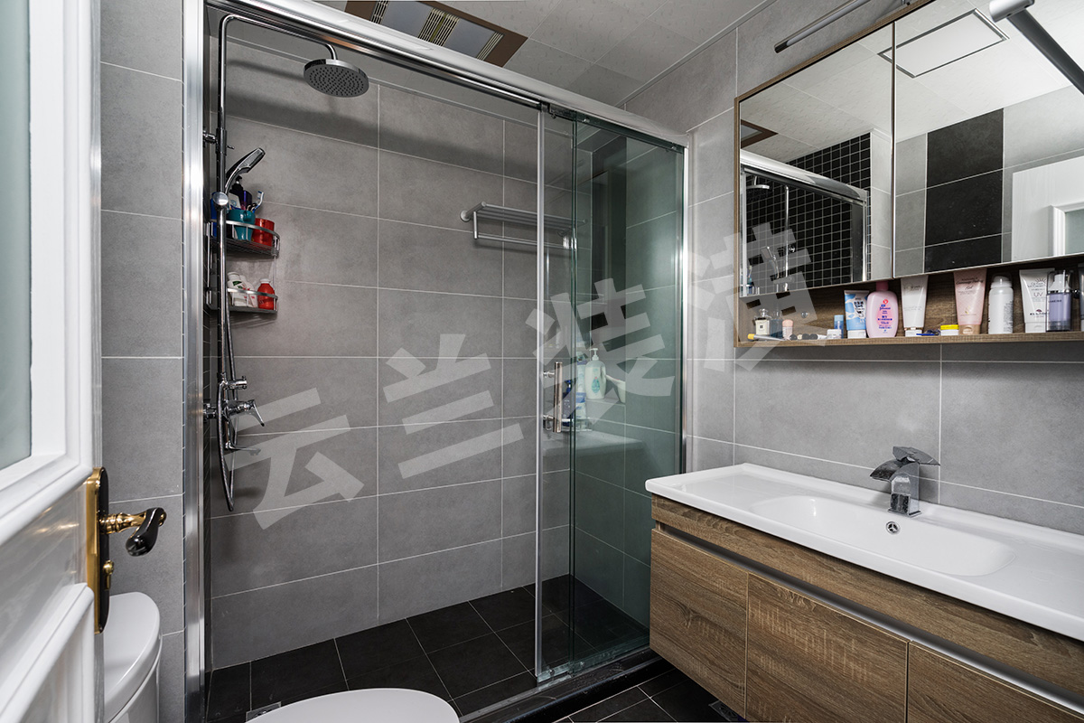 衛(wèi)生間干凈明亮，主色調采用淡淡的灰色，但是又不想過于單調，所以在掛花灑那面墻面采用了深色馬賽克，還有在馬桶背后也采用深色面磚加于修飾。
