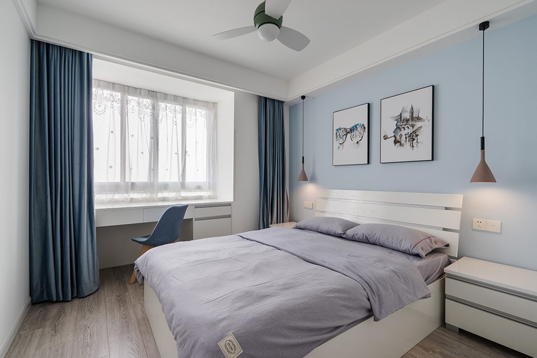  臥室爽朗大氣的線條勾勒出干練的個(gè)性氣息，為了不打破安逸舒適的空間感，陶瓷色的床頭燈與藍(lán)灰色的布藝窗簾恰到好處的降低空間過(guò)于高調(diào)活躍的色彩基調(diào)，同時(shí)襯托富有質(zhì)感的裝飾畫(huà)，淺紫色軟麻布床單搭配出豐富的層次感，傳遞專屬現(xiàn)代主義的奢華、溫馨、向往自由的風(fēng)格，舒緩了人的緊張心情，讓人坦然釋放，回歸自我。
