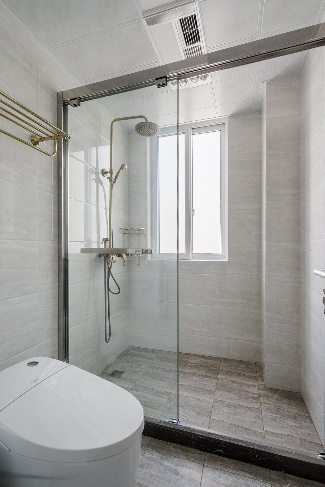 衛(wèi)生間，則是簡(jiǎn)單的材質(zhì)對(duì)比，襯托出每種材質(zhì)特有的性格和溫度。如原木色的臺(tái)盆柜、半透明的不銹鋼夾絲玻璃，都有它們特有的屬性。干濕區(qū)的過(guò)渡也不會(huì)對(duì)采光造成影響。值得一體的是臺(tái)盆柜上方的鏡前燈，簡(jiǎn)潔明了，臺(tái)盆柜下端的這部分空間更是合情合理的考慮了衛(wèi)生的清理。
