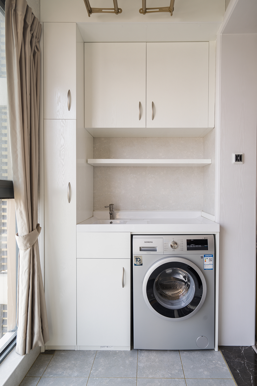 而本案空間采用原木色系的色調(diào)，主空間靜謐藍(lán)的沙發(fā)背景和紋理清晰的木飾面電視背景相互呼應(yīng)。同時(shí)靜謐藍(lán)的背景襯托了淡灰色輕奢的布藝家具及軟裝畫(huà)，讓空間不在拘謹(jǐn)，在陶瓷白的茶幾的對(duì)比下產(chǎn)生色彩的碰撞，造型簡(jiǎn)潔的家具設(shè)計(jì)透露出幾分優(yōu)雅怡然的空間氣質(zhì)。
