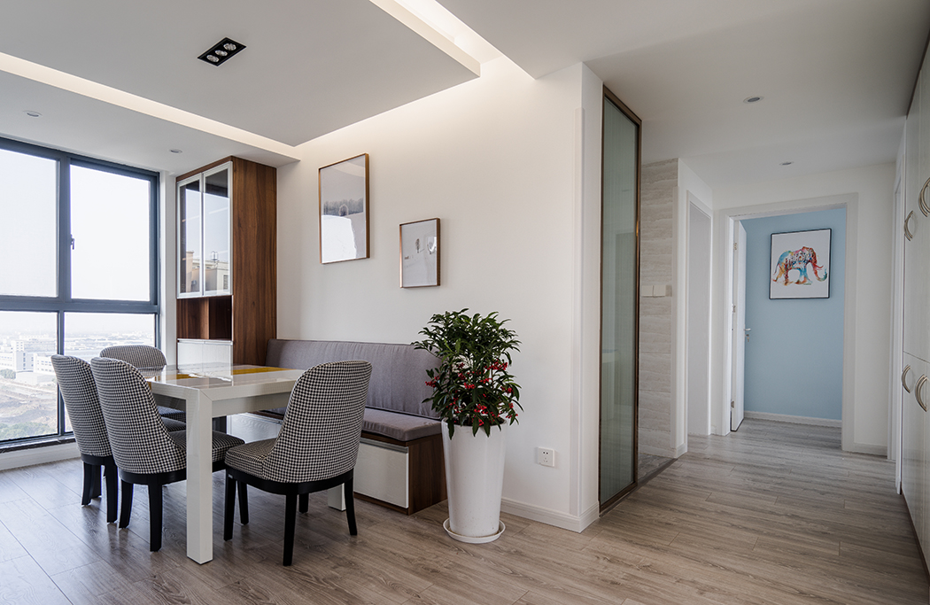 餐區(qū)通過(guò)大體塊的墻頂體留白和溫潤(rùn)細(xì)膩的地板色形成對(duì)比，與此呼應(yīng)的是同色調(diào)的餐桌椅，而綠色、玫瑰金的邊框色則延續(xù)了主空間的點(diǎn)綴色，淺紫色的抽象裝飾畫(huà)與餐桌旁邊的綠植、夾絲玻璃的金屬色作為一個(gè)整體貫穿于整個(gè)空間，點(diǎn)燃了熱情。冷暖色調(diào)的跳躍搭配豐富整體設(shè)計(jì)的層次感，而華麗精美的射燈造型，傾瀉出迷醉溫柔的燈光讓空間每一件家具飾品都成為無(wú)可挑剔，不可或缺的藝術(shù)品。
