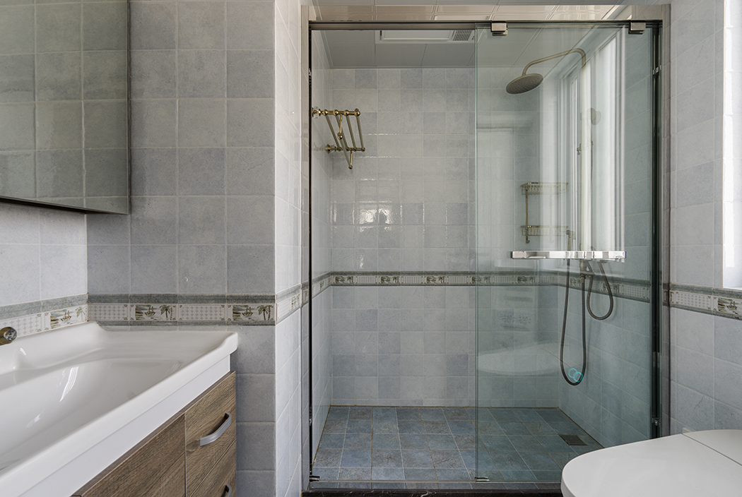 衛(wèi)生間，則是簡(jiǎn)單的材質(zhì)對(duì)比，襯托出每種材質(zhì)特有的性格和溫度。如原木色的臺(tái)盆柜、半透明的不銹鋼夾絲玻璃，都有它們特有的屬性。干濕區(qū)的過(guò)渡也不會(huì)對(duì)采光造成影響。值得一體的是臺(tái)盆柜上方的鏡前燈，簡(jiǎn)潔明了，臺(tái)盆柜下端的這部分空間更是合情合理的考慮了衛(wèi)生的清理。