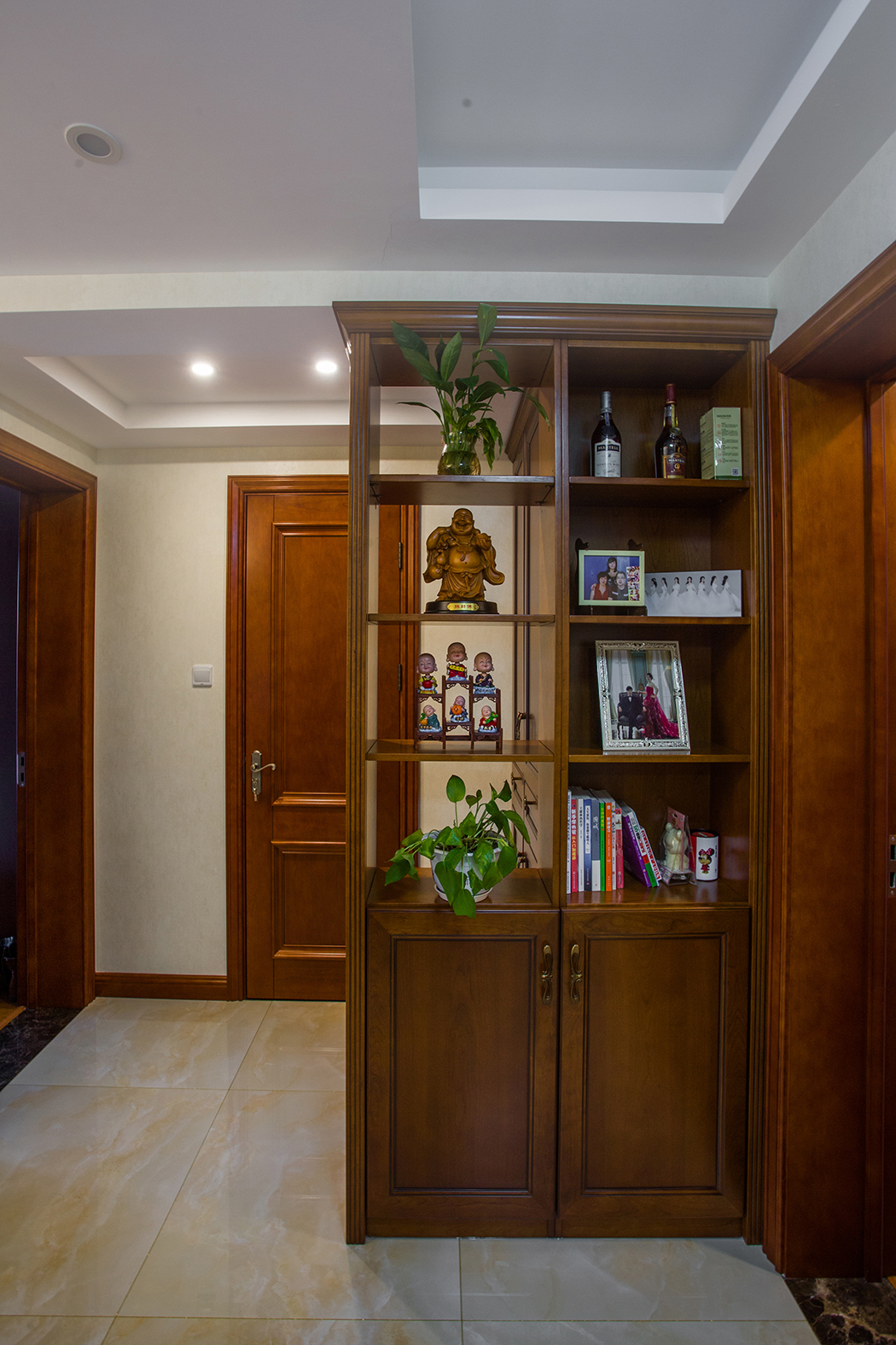 玄關處采用整體定制玄關，既美觀而又通透，即避開衛生間的門和入戶門的沖突，又起到點綴生活的作用，舊時的照片，喚起業主家庭生活的美滿。