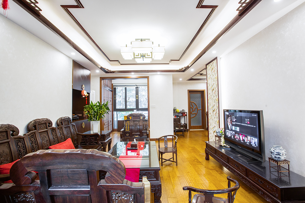 客廳吊頂與餐廳吊頂相統一，但只有這些也是不夠的，將中式元素的花鳥壁紙設計在電視背景墻之中，看起來就像兩扇中式屏風，加入木線條更顯沉穩內斂。

