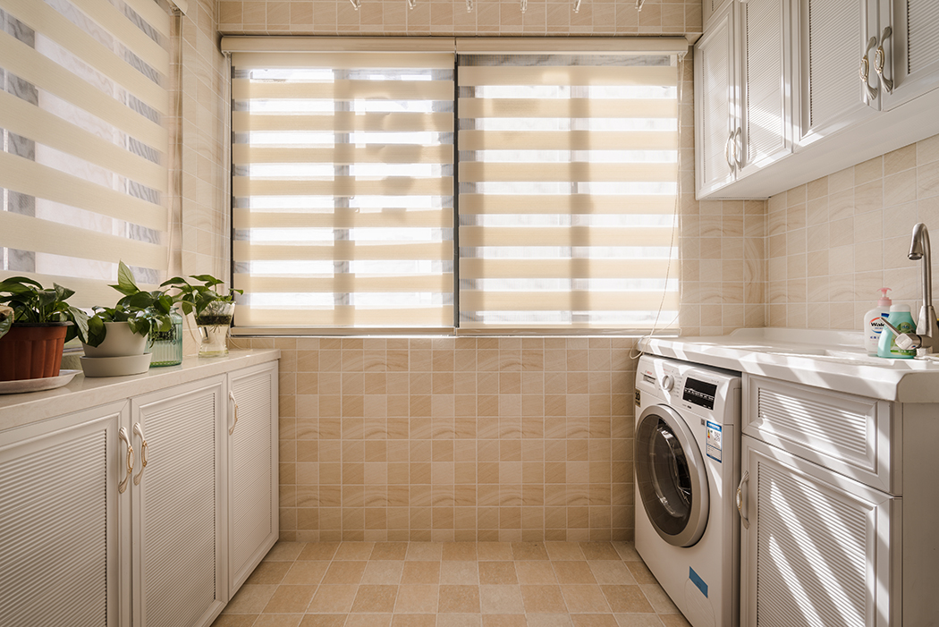 花格子墻磚，半通透式的窗簾，成品洗衣搭檔，使整體陽臺美觀與實用完美結合，矮柜上的綠色盆景，為整個空間增添了一份活力。
