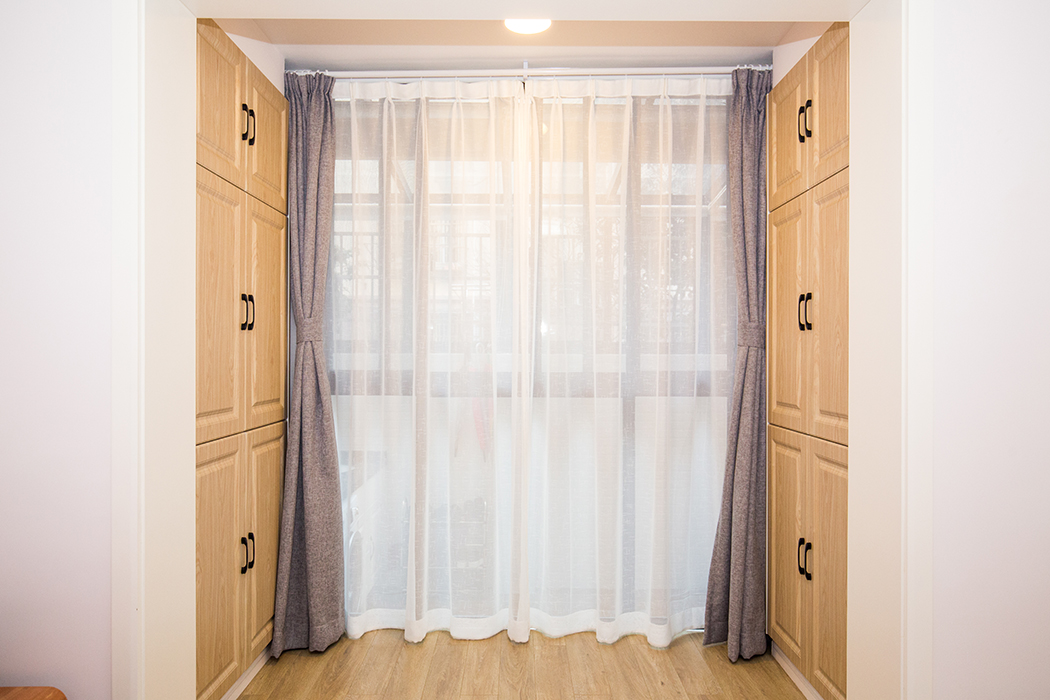 房間以原木色為主，落地玻璃可以讓陽光全曬進來，原本陽臺區域擴到房間，還增加了兩面儲物柜，房間以溫暖舒適為主。
