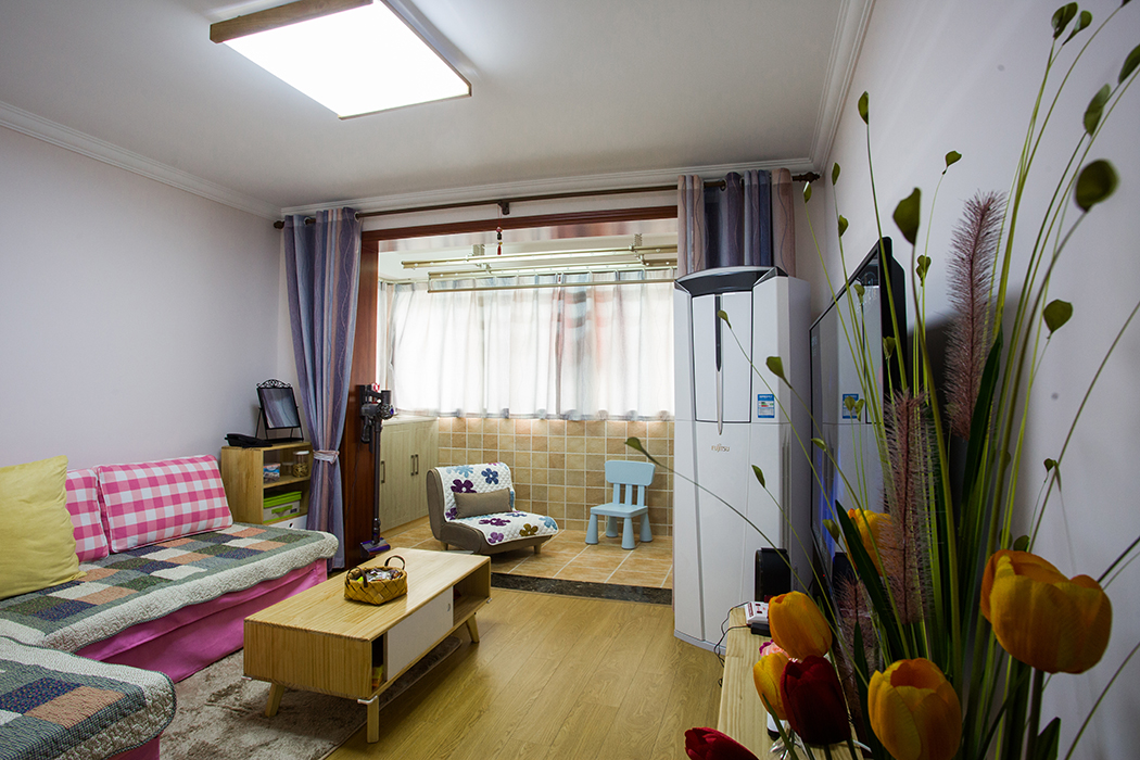 空間從色彩到材質到家具的選擇，盡顯簡約與舒適氣息。整個空間以亮色為主色調，現代的硬朗線條和咖北歐家具的組合，有種現代線條感。客廳亮色絨面沙發與粉紅靠墊、原木邊柜組合增添幾分歡快與質感。
