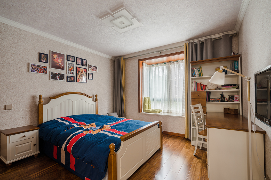 次臥還是征求了業(yè)主兒子的喜好，以現(xiàn)代偏英倫風(fēng)格來(lái)裝飾，墻頂面都改用墻紙來(lái)打底和臥室客廳風(fēng)格完全不同，但局部的深色家具很好的呼應(yīng)了門(mén)套和窗套，讓區(qū)域和區(qū)域也融入一體。
