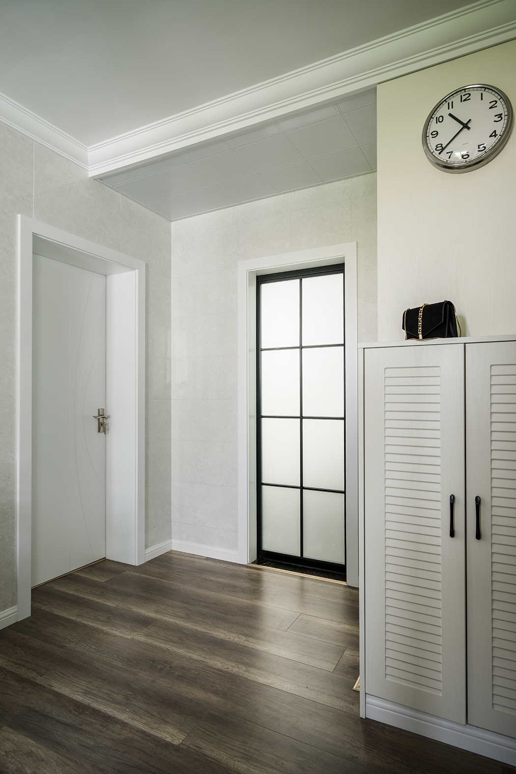 客餐廳的背景采用了白色文化石，作為餐廳的背景材料增加了整體的檔次，玄關鞋柜上的小鐘更突顯出業主是個注重時間效率的人。整體的室內設計，以現代簡約為主，配以極簡現代又時尚的風格點綴。百葉門的鞋柜對整體風格也起到提亮的效果。