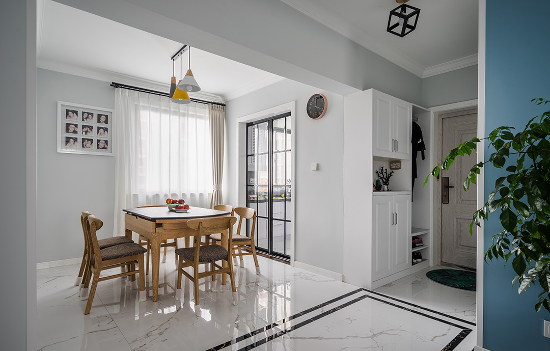 在餐廳的設計上，我們延續了客廳的灰調，明黃色餐廳燈給整個空間多了一絲明快，原木色的餐椅以及深色坐墊現代感分明，淺色窗簾元素中削減了空間的硬度。黑色格子玻璃門與餐廳風格保持協調統一。
