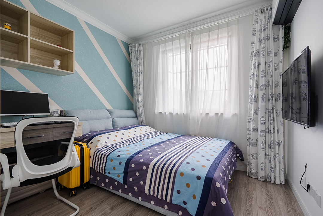 小孩房背景墻用幾何色塊打破單調氛圍，床品依舊是香芋色為主，圓點點綴。選用白色卡通圖案窗簾，增加了些許童真。
