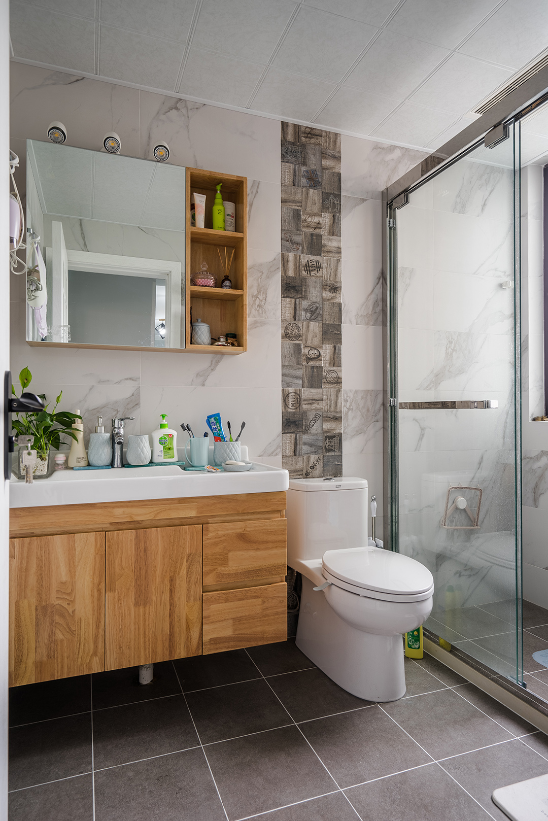 衛生間灰色地磚配上白色墻磚層次分明，馬桶背后的腰帶設計點亮了整個空間。
