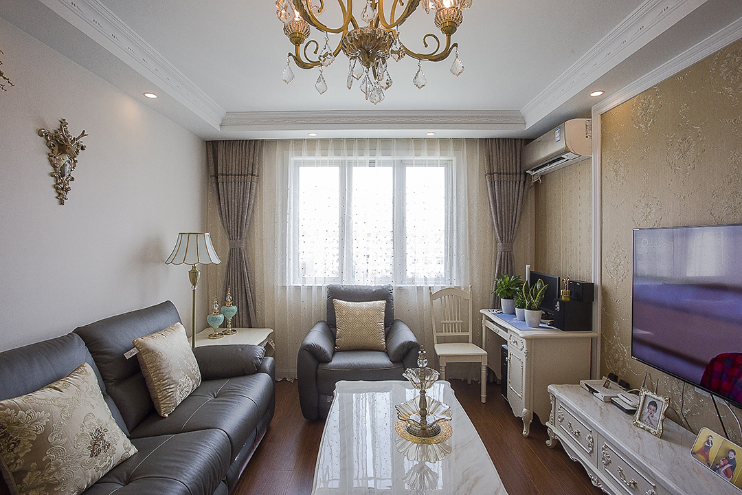 客廳采有光潔大氣的地磚，使得深色沙發(fā)不再壓抑，也更凸顯了家具的質(zhì)感，品質(zhì)生活油然而生。歐式家具低調(diào)而奢華，沉穩(wěn)而大氣，充分體現(xiàn)了業(yè)主的，低調(diào)而內(nèi)斂的做人風(fēng)格。電視背景墻的線框采用的實木線條，中間采用的是當(dāng)下比較流行的微晶石，兩邊菱形抽邊境，顯得端莊大氣。
