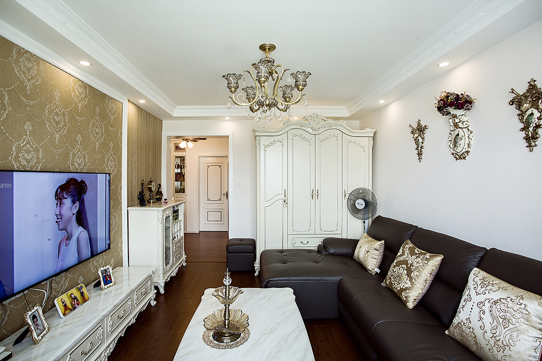 客廳采有光潔大氣的地磚，使得深色沙發(fā)不再壓抑，也更凸顯了家具的質(zhì)感，品質(zhì)生活油然而生。歐式家具低調(diào)而奢華，沉穩(wěn)而大氣，充分體現(xiàn)了業(yè)主的，低調(diào)而內(nèi)斂的做人風(fēng)格。電視背景墻的線框采用的實木線條，中間采用的是當(dāng)下比較流行的微晶石，兩邊菱形抽邊境，顯得端莊大氣。

