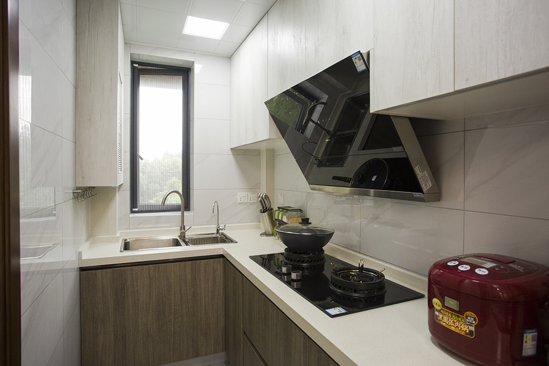 廚房間爵士白的墻磚，作為背景色簡(jiǎn)單卻不失大氣，櫥柜上淺下深，更給人以踏實(shí)輕快的感覺(jué)，胡桃木色配上白色木紋的櫥柜，沒(méi)有歐式的奢華，卻多了現(xiàn)代的簡(jiǎn)約和美式的恬淡。
