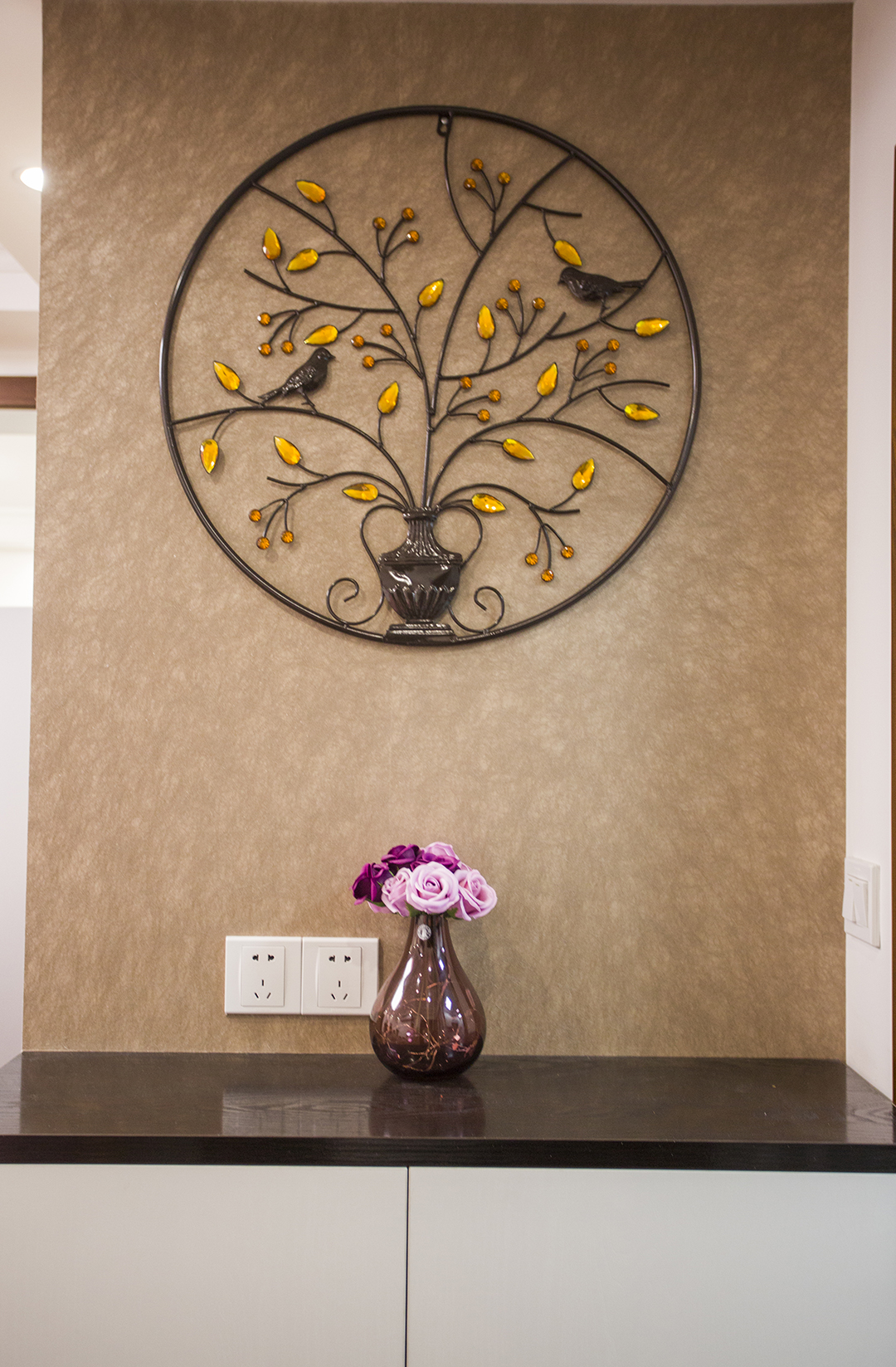 一進(jìn)門的玄關(guān)是夫妻最滿意的一點(diǎn)，一是區(qū)分了室內(nèi)外空間，做到了室內(nèi)外的分割，讓小戶型也有了大戶型的莊重感，深色壁紙配上純白色柜子，大方的同時(shí)不失輕快.墻面鐵藝工藝品更是畫龍點(diǎn)睛的突出了主人低調(diào)奢華的品味.